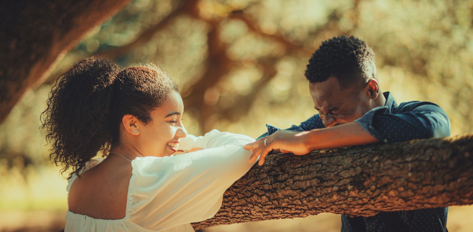 A joyful couple laughing together outdoors at golden hour